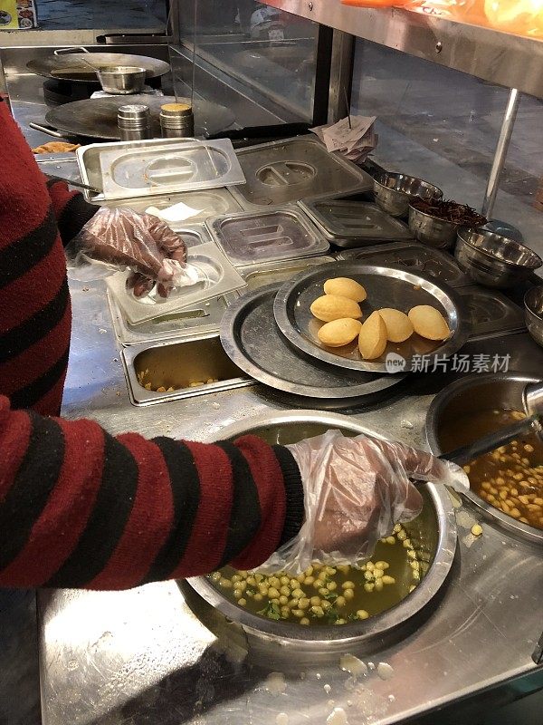 印度街头小吃的形象，panipuri / panipuri / golgappa，调味水(薄荷/马沙拉)，鹰嘴豆，卫生食品手套